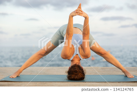 Yoga practice on embankment, female athlete fulfil carry out Prasarita Padottanasana Yoga practice on embankment, female athlete fulfil carry out Prasarita Padottanasana 134124765