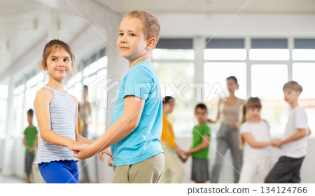 Happy preteen children practicing ballroom dances in pairs in training hall Happy preteen children practicing ballroom dances in pairs in training hall 134124766