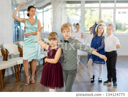Little children in elegant dresses practicing waltz dance in school hall Little children in elegant dresses practicing waltz dance in school hall 134124775