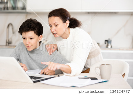 Boy studiyng, mother helping 134124777