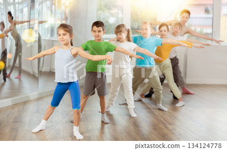 Children do warm-up exercises in studio, prepare for pair dance class Children do warm-up exercises in studio, prepare for pair dance class 134124778