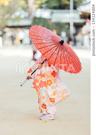 A girl holding a Japanese umbrella and visiting a shrine for Shichi-Go-San A girl holding a Japanese umbrella and visiting a shrine for Shichi-Go-San 134124804