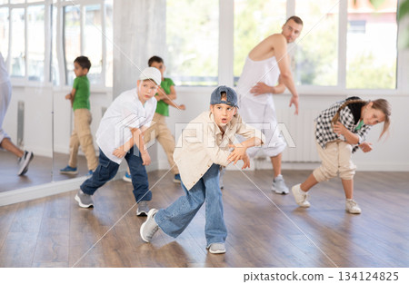 Preteen girl practicing hip hop choreography with peers and instructor 134124825