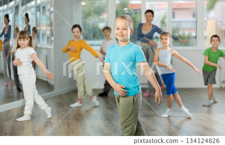Boy learn to dance modern dances, repeat movement with unrecognizable teacher. 134124826