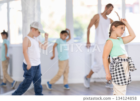 Group of happy teens in casual clothes with male teacher practicing hip hop in dance studio Group of happy teens in casual clothes with male teacher practicing hip hop in dance studio 134124858