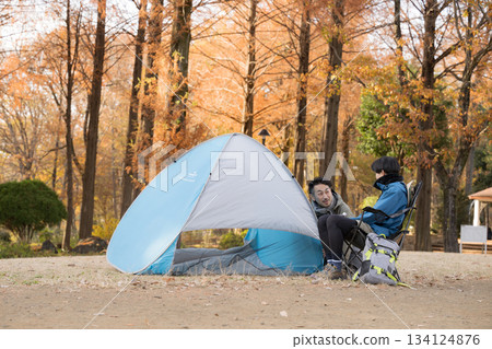 一位獨自露營的男士在秋季露營地的椅子上放鬆身心,享受戶外樂趣。 一位獨自露營的男士在秋季露營地的椅子上放鬆身心,享受戶外樂趣。 134124876