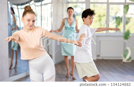 Smiling teenage girl practicing jitterbug with partner in dance studio 134124882