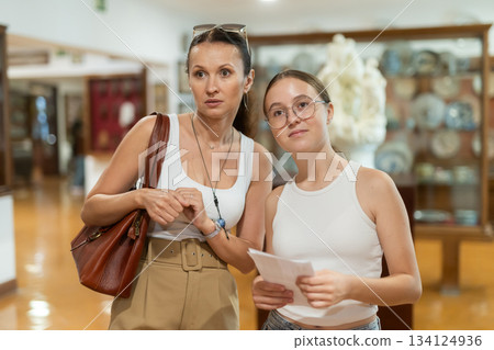 Young woman with teen daughter walk around museum, cookware zone. Young woman with teen daughter walk around museum, cookware zone. 134124936