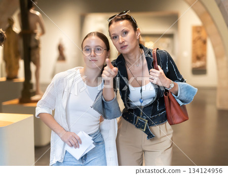 Young woman with teen daughter walk around museum, view sculpture in museum hall 134124956