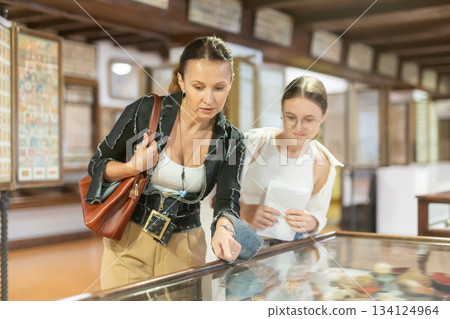Woman and teenage girl looking at exhibit in museum display Woman and teenage girl looking at exhibit in museum display 134124964