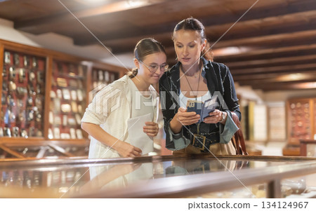 Teen daughter and woman mother with phone walk around museum 134124967