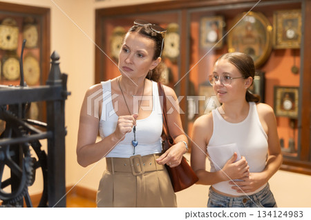 Young woman with teen daughter walk around museum, view clock Young woman with teen daughter walk around museum, view clock 134124983