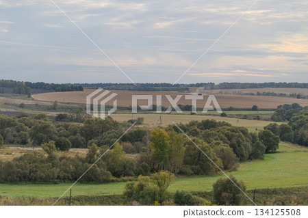 A Serene Countryside Landscape Featuring Beautiful Rolling Fields Beneath an Overcast Sky 134125508