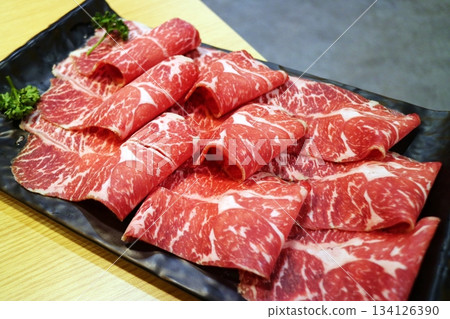 黑色盤子上擺放著切成薄片的生牛肉。 134126390