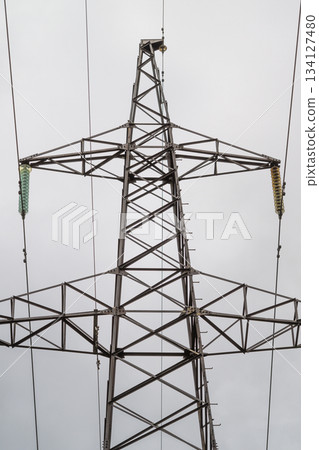 A High Voltage Power Transmission Tower Stands Tall Against a Dramatic Cloudy Sky Above 134127480