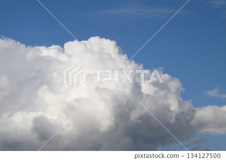 Fluffy white clouds drift against a deep blue sky, creating a serene atmosphere 134127500