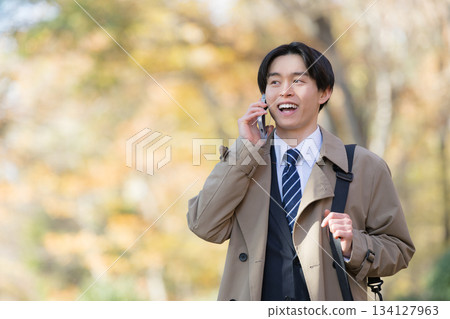 一位身穿外套的男子在秋葉掩映的戶外進行銷售拜訪。 134127963