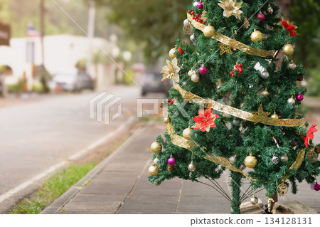 Christmas tree decorated with balloons and a yellow shiny ribbon with sequins on the street of Phuket during the day in Thailand, close-up, Christmas. New Year's Eve in Southeast Asia. High quality Christmas tree decorated with balloons and a yellow shiny ribbon with sequins on the street of Phuket during the day in Thailand, close-up, Christmas. New Year's Eve in Southeast Asia. High quality 134128131