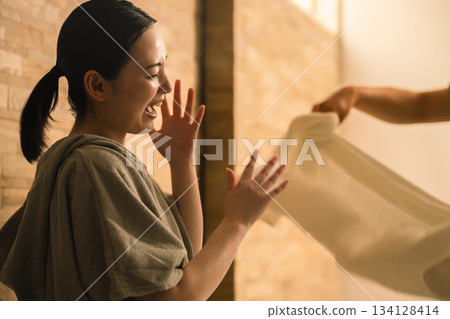 A young man applying heat waves to a young woman with a towel. Beauty image A young man applying heat waves to a young woman with a towel. Beauty image 134128414