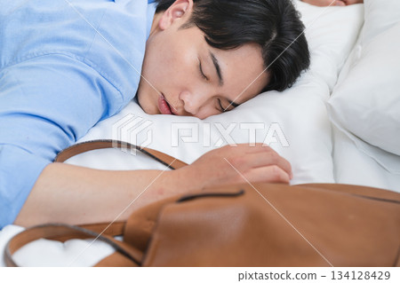 A young man who falls asleep in bed and wakes up in the morning 134128429