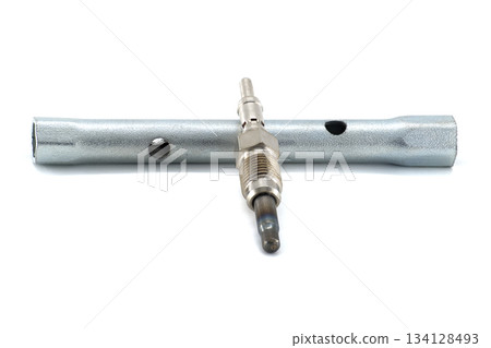 A glow plug rests on a wrench, ready for automotive maintenance, isolated against white. 134128493