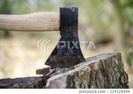 Axe Embedded in a Log During Firewood Chopping in a Forest Setting Axe Embedded in a Log During Firewood Chopping in a Forest Setting 134128494
