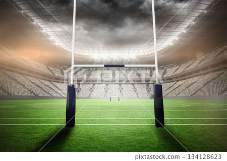 Pair of upright goalposts standing in stadium under curved roof with grass field and floodlights Pair of upright goalposts standing in stadium under curved roof with grass field and floodlights 134128623