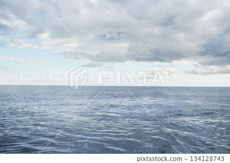Flat design calm ocean is being shown reaching distant horizon under partly cloudy sky with ripples Flat design calm ocean is being shown reaching distant horizon under partly cloudy sky with ripples 134128743