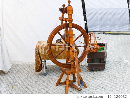 Old Slavic spinning wheel made of wood, symbol of Russian folk culture and traditional handicraft. Historical village style and handmade art. Old Slavic spinning wheel made of wood, symbol of Russian folk culture and traditional handicraft. Historical village style and handmade art. 134129082