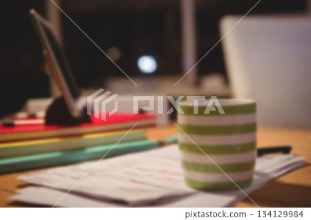 Coffee cup over papers by digital tablet 134129984