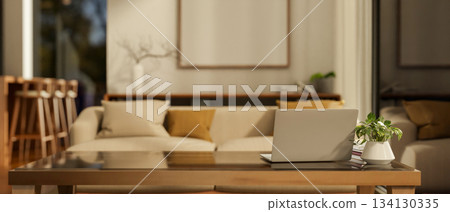 White laptop on glass top wooden table with potted plants aside in a hotel lounge or dining hall. White laptop on glass top wooden table with potted plants aside in a hotel lounge or dining hall. 134130335