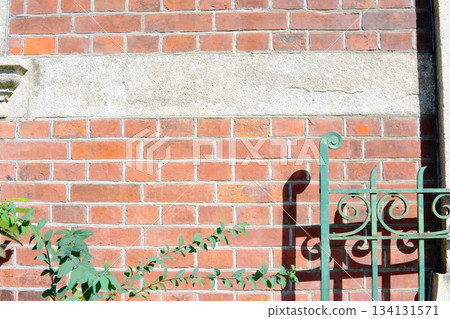 Green decorative iron fence and classic red brick wall Green decorative iron fence and classic red brick wall 134131571