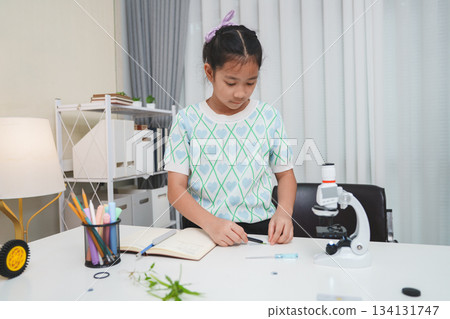 Child looking through microscope on white background. Kid scientist learning biology. 134131747