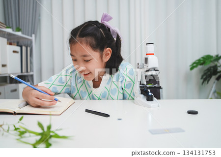 Elementary School Girl Taking Notes Science Experiment Microscope STEM Research Elementary School Girl Taking Notes Science Experiment Microscope STEM Research 134131753