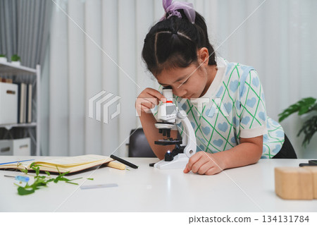 Elementary student practicing science skills using microscope during hands on learning activity 134131784