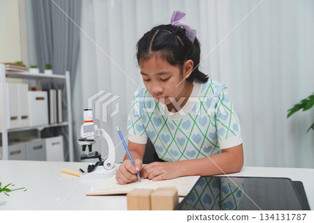 Elementary School Girl Taking Notes Science Experiment Microscope STEM Research 134131787