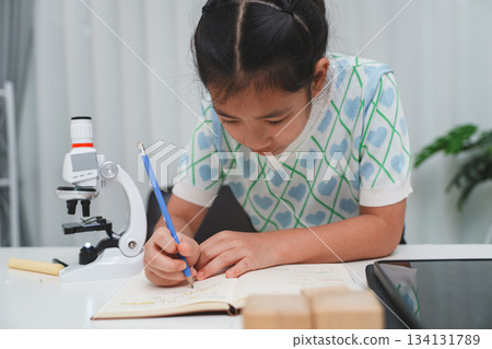 Elementary School Girl Taking Notes Science Experiment Microscope STEM Research Elementary School Girl Taking Notes Science Experiment Microscope STEM Research 134131789