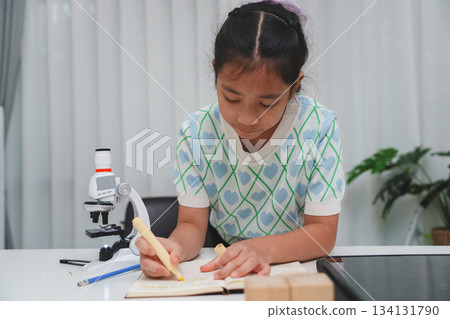 Elementary School Girl Taking Notes Science Experiment Microscope STEM Research Elementary School Girl Taking Notes Science Experiment Microscope STEM Research 134131790