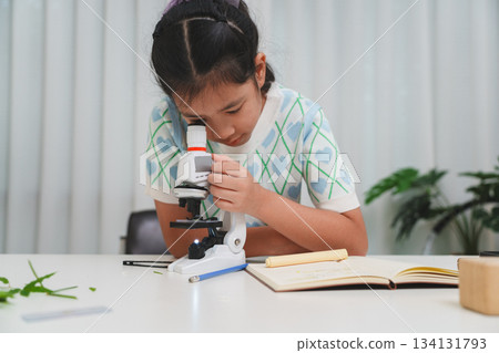 Elementary student practicing science skills using microscope during hands on learning activity 134131793