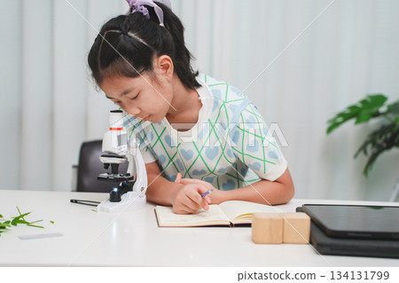 Elementary student practicing science skills using microscope during hands on learning activity 134131799