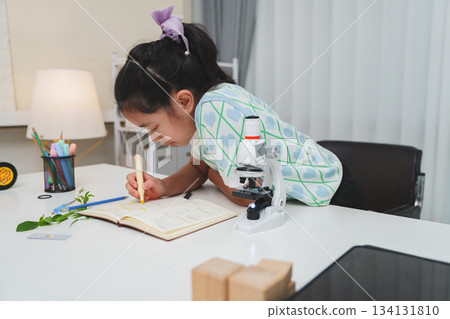Elementary School Girl Taking Notes Science Experiment Microscope STEM Research Elementary School Girl Taking Notes Science Experiment Microscope STEM Research 134131810