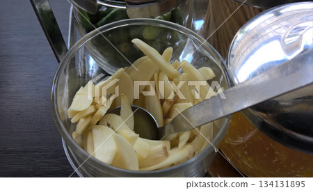 Sliced garlic metal spoon glass bowl chili green pepper condiment station kitchen raw fresh spicy aroma cooking ingredient Sliced garlic metal spoon glass bowl chili green pepper condiment station kitchen raw fresh spicy aroma cooking ingredient 134131895