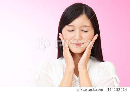 一位女子輕輕撫摸著自己的臉頰 一位女子輕輕撫摸著自己的臉頰 134132424