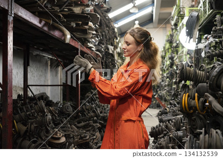 Female technician worker working in garage scrap yard old car part workshop warehouse. 134132539