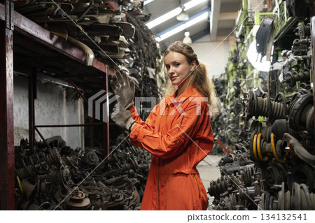 Female technician worker working in garage scrap yard old car part workshop warehouse. 134132541