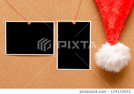 Blank photos are pinned to the board. Santa's hat on a cork board. Blank photos are pinned to the board. Santa's hat on a cork board. 134132652
