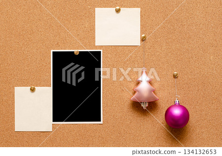 Empty photos and Christmas tree toys are pinned on a cork board. Copy space 134132653