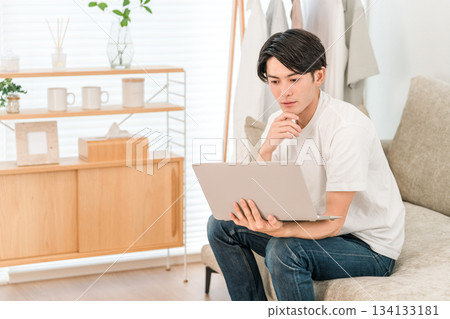 A young Asian man sitting on a sofa and using a computer (freelance, creator, programmer) A young Asian man sitting on a sofa and using a computer (freelance, creator, programmer) 134133181