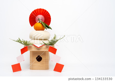 A photo of a real rice cake, "Kagamimochi," placed on the left, on a white background with a sanpo (pedestal) 134133530