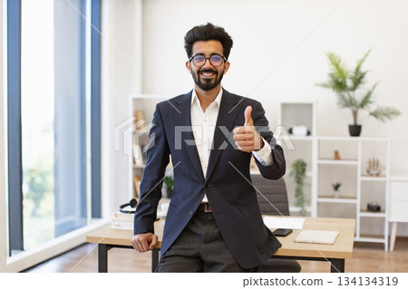 An Indian businessman in a suit gives a thumbs up, showing approval and success An Indian businessman in a suit gives a thumbs up, showing approval and success 134134319